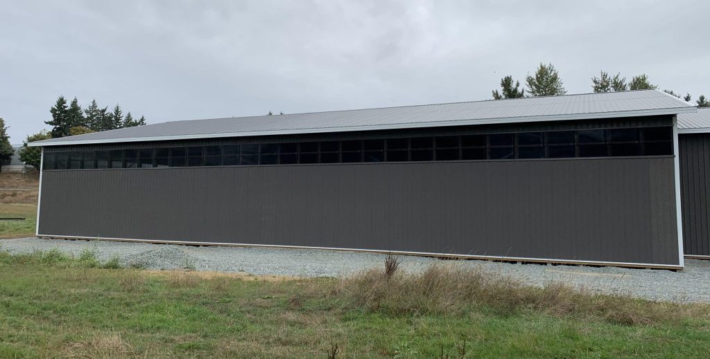 A charcoal post-frame equestrian riding arena