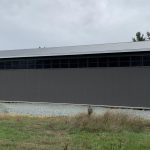 A charcoal post-frame equestrian riding arena