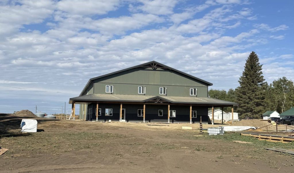 A dark sage post-frame accessory building with an agricultural shop and barn