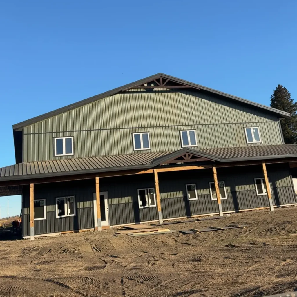 A dark sage post-frame accessory building with an agricultural shop and barn