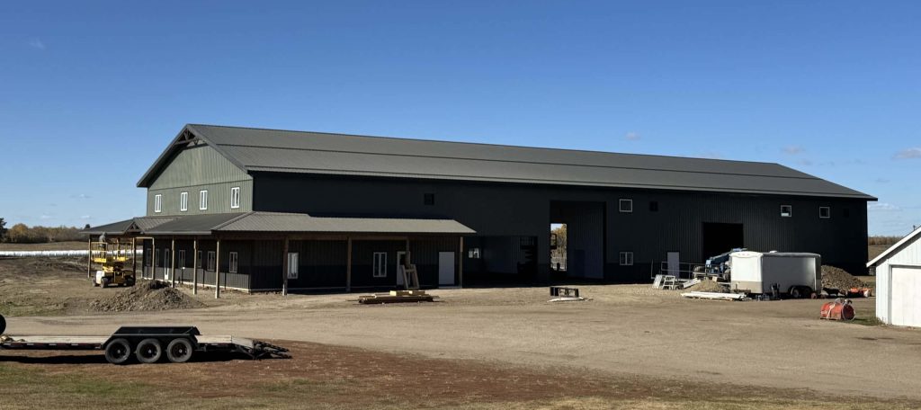 A dark sage post-frame accessory building with an agricultural shop and barn