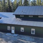 A post-frame melchers green residential barndominium with an attached garage