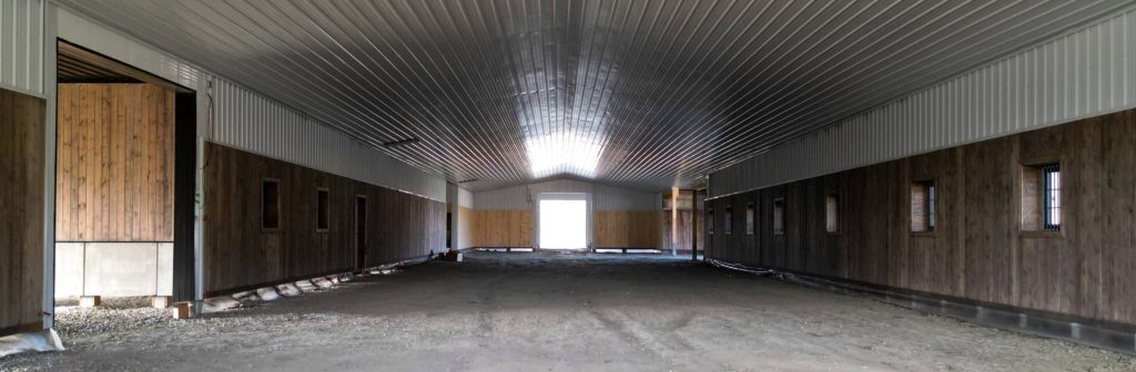 A stone grey post-frame equestrian riding Arena