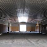 A stone grey post-frame equestrian riding Arena