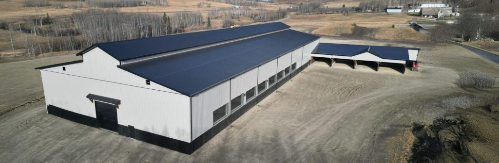 A stone grey post-frame equestrian riding Arena