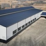 A stone grey post-frame equestrian riding Arena