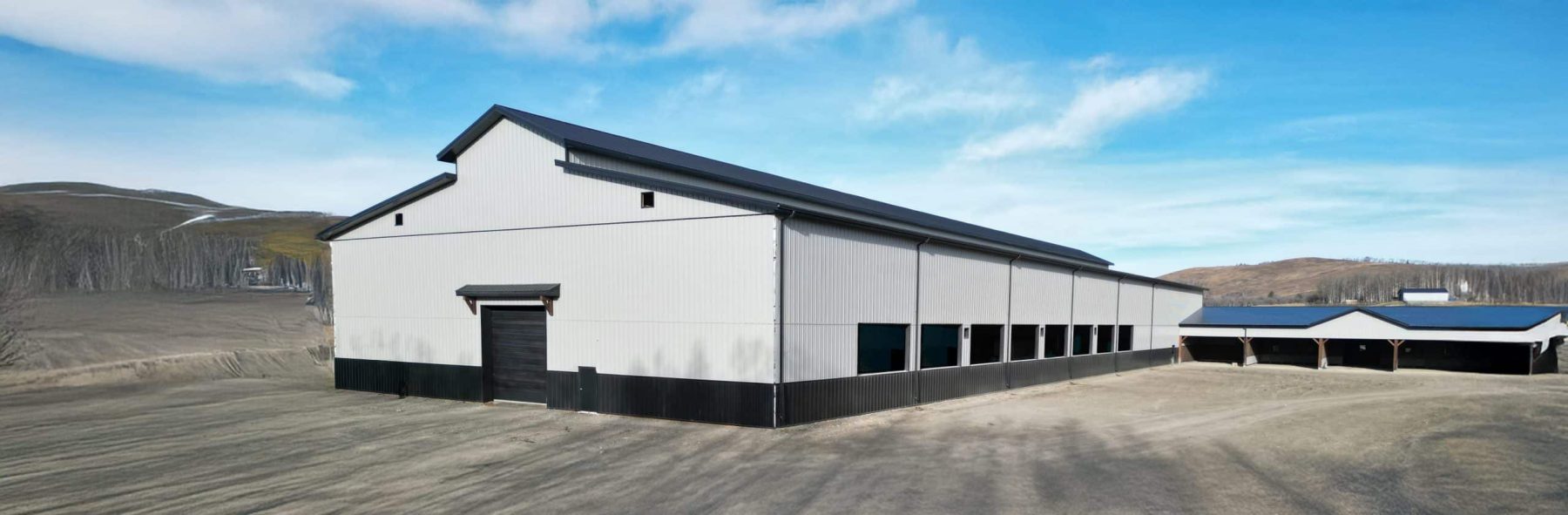 A stone grey post-frame equestrian riding Arena