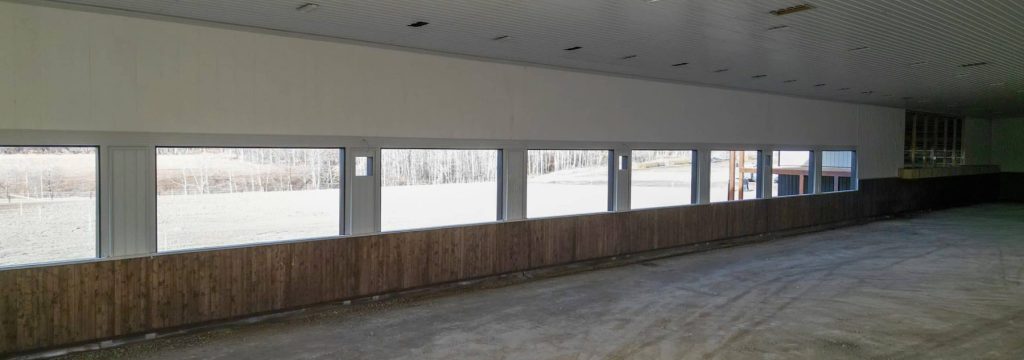 A stone grey post-frame equestrian riding Arena