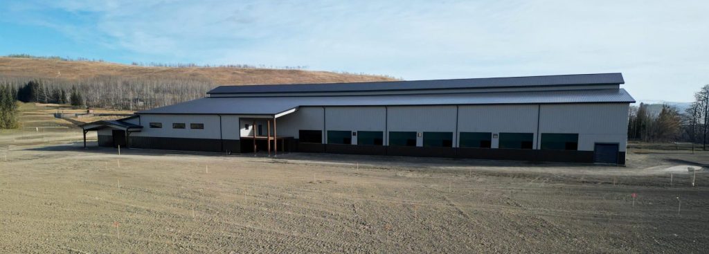 A stone grey post-frame equestrian riding Arena