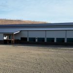 A stone grey post-frame equestrian riding Arena