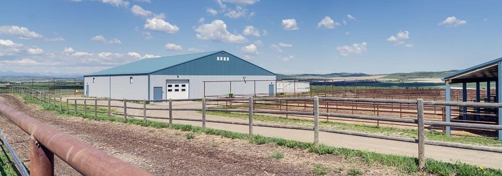 A post-frame equestrian barn with overhead doors and white walls