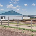 A post-frame equestrian barn with overhead doors and white walls
