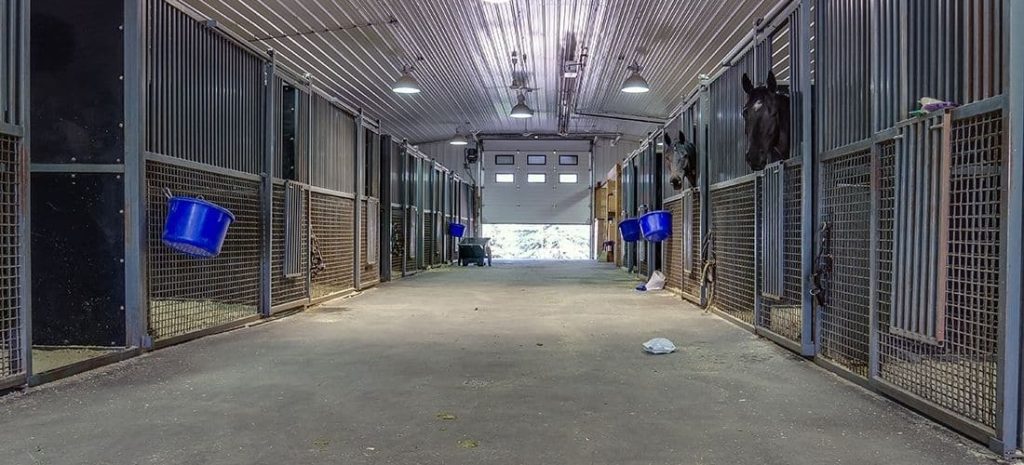 A post-frame equestrian barn with overhead doors and white walls
