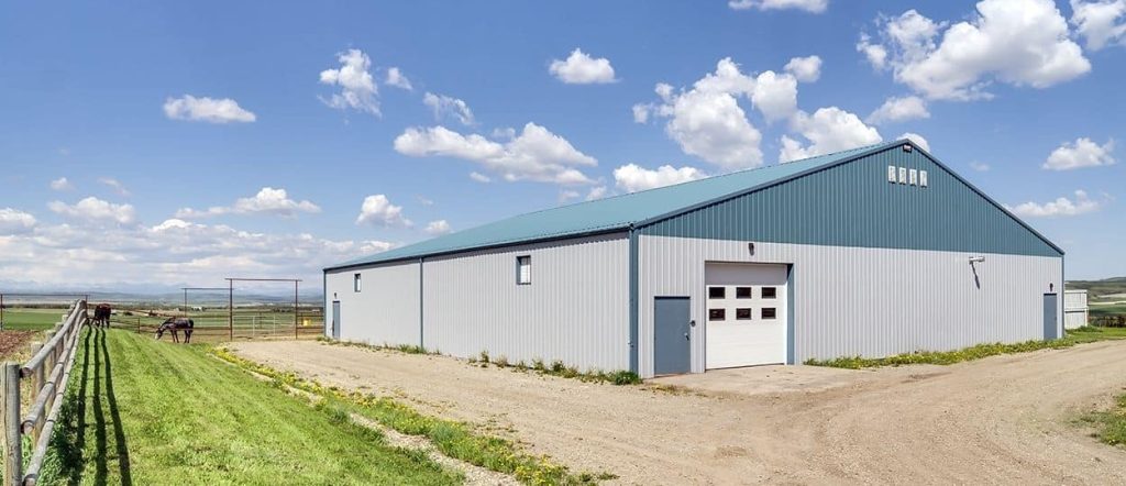 A post-frame equestrian barn with overhead doors and white walls