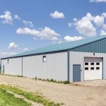 A post-frame equestrian barn with overhead doors and white walls