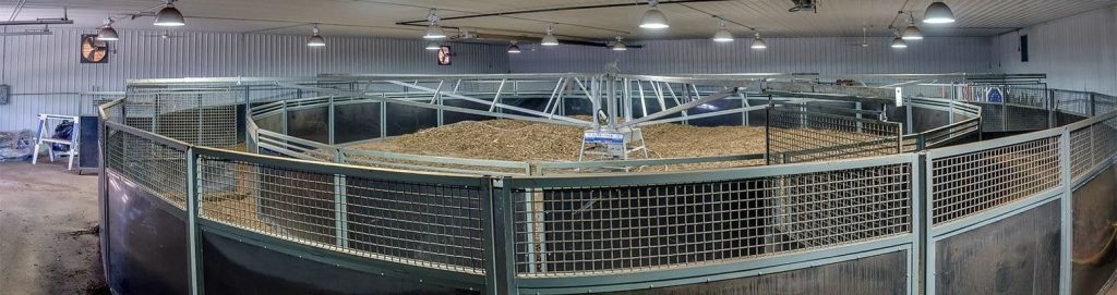 A post-frame equestrian barn with overhead doors and white walls