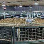 A post-frame equestrian barn with overhead doors and white walls