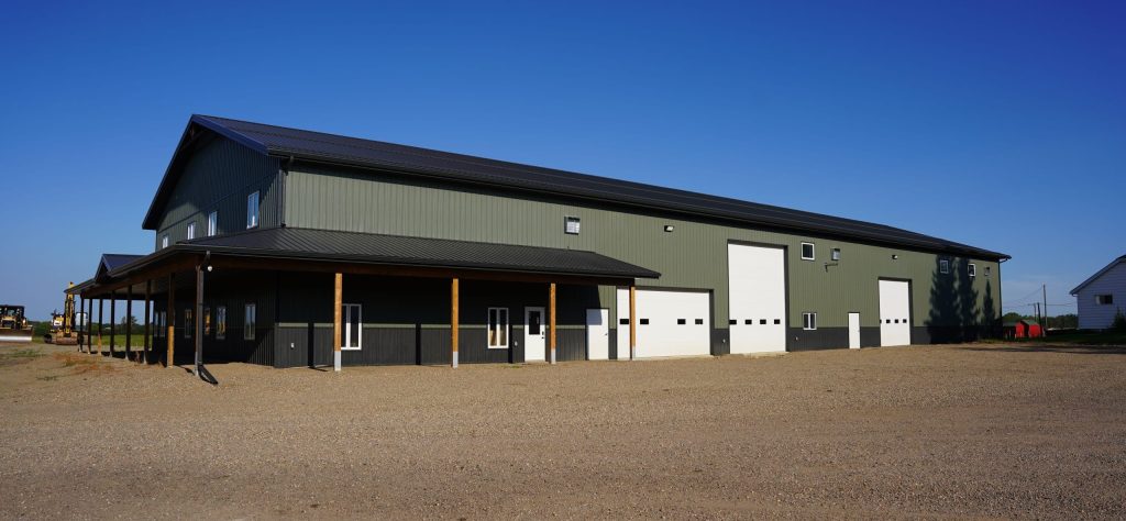 A dark sage post-frame accessory building with an agricultural shop and barn