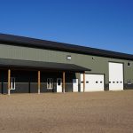 A dark sage post-frame accessory building with an agricultural shop and barn