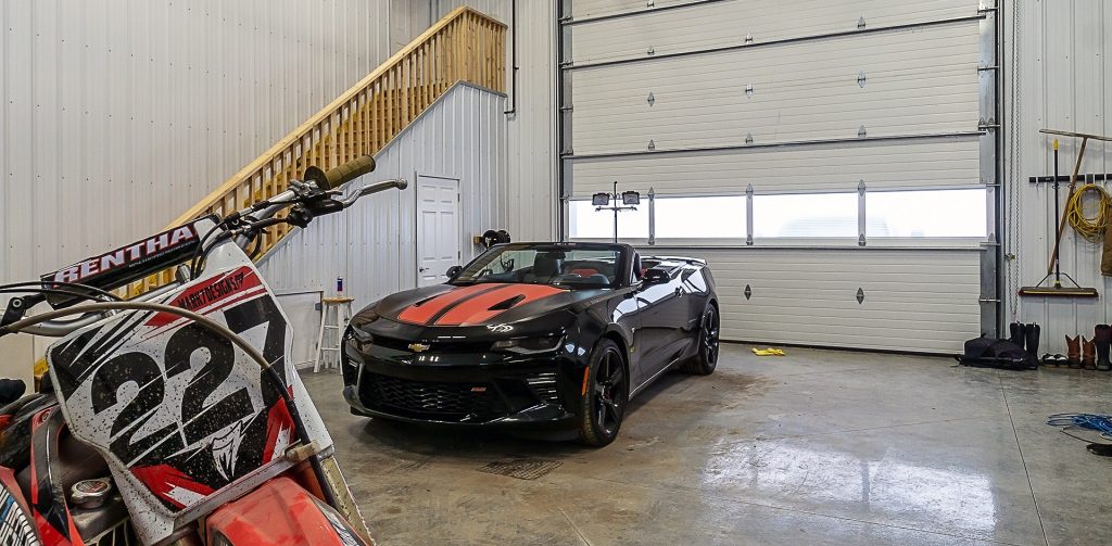 A black post-frame lifestyle & hobby shop with soffits and a overhead door