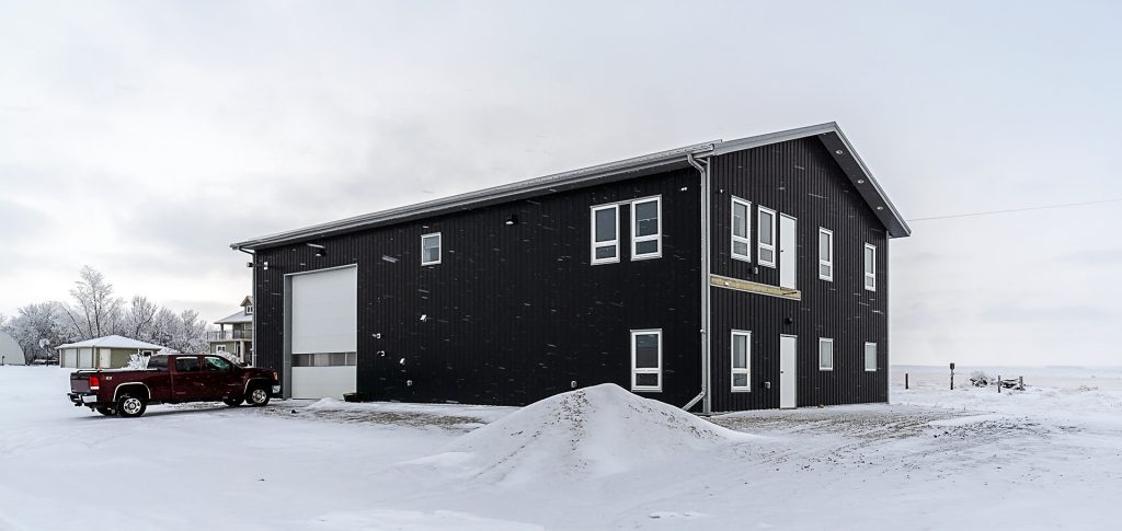 A black post-frame lifestyle & hobby shop with soffits and a overhead door