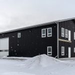 A black post-frame lifestyle & hobby shop with soffits and a overhead door