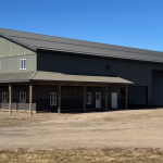 Post-frame residential building - The Shouse in greed metal cladding and a wrap-around porch in Saskatchewan
