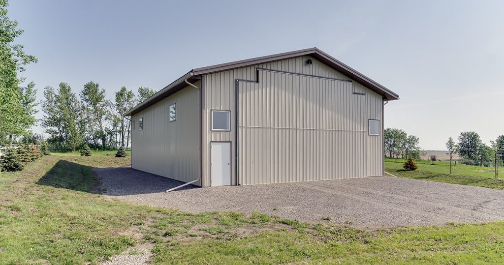 A light stone post-frame lifestyle & hobby shop with a bi-fold door and dark brown roof