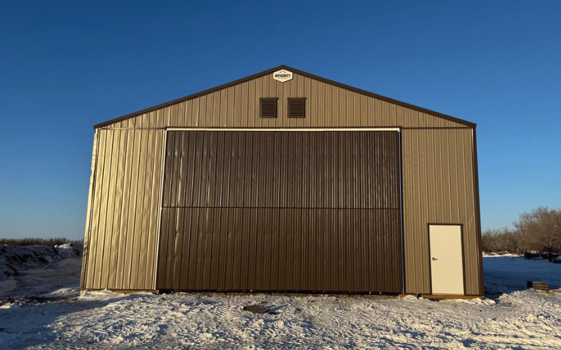 A buckskin post-frame agricultural shop with a coffee brown bifold door