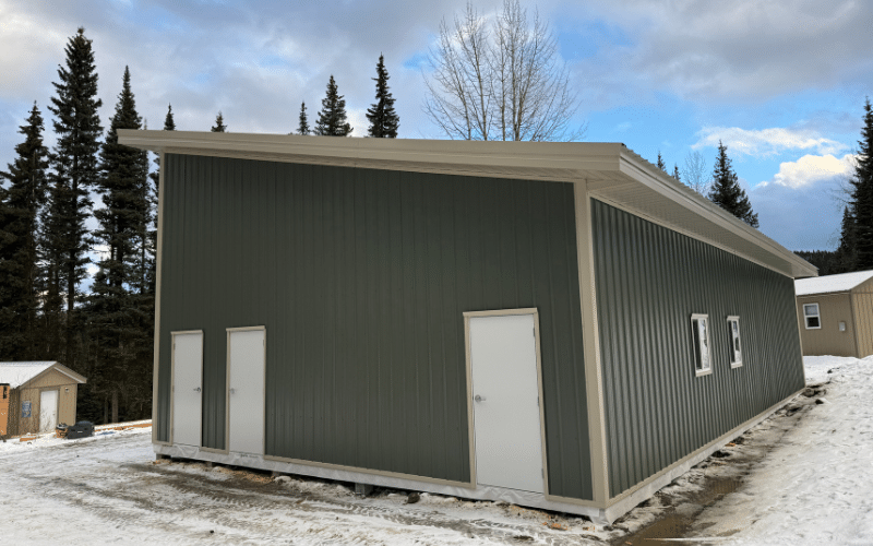 A dark sage post-frame lifestyle and hobby storage building with soffits and overhead doors