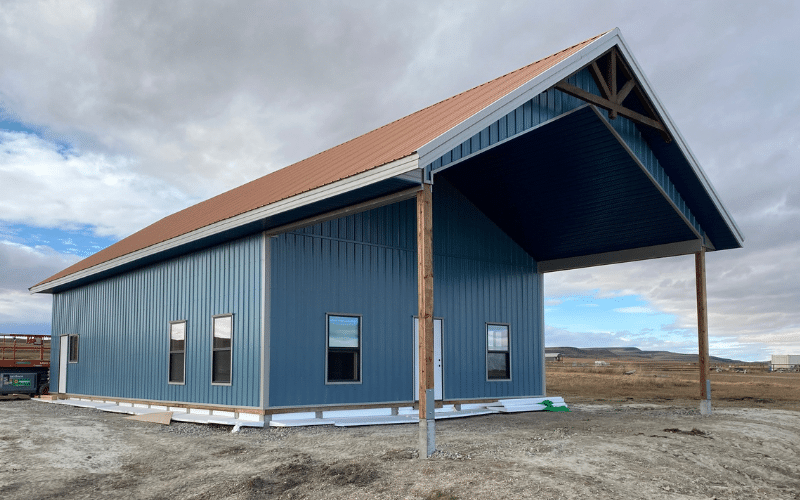 A slate blue post-frame custom shouse & Barndo with open lean-to