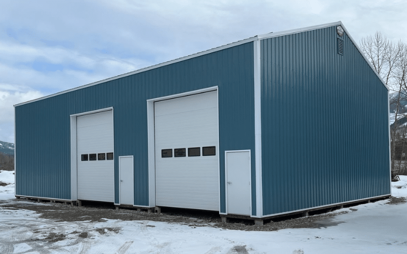 A slate blue post-frame agricultural shop with overhead doors