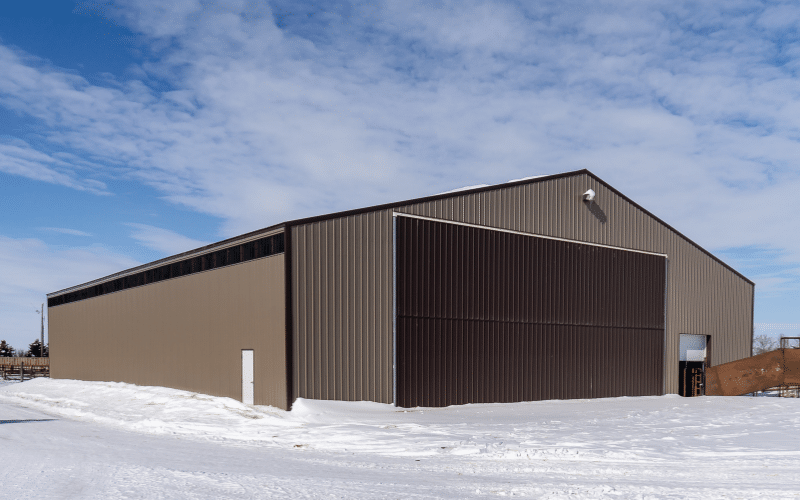 A buckskin post-frame agricultural Machine shed with a bifold door
