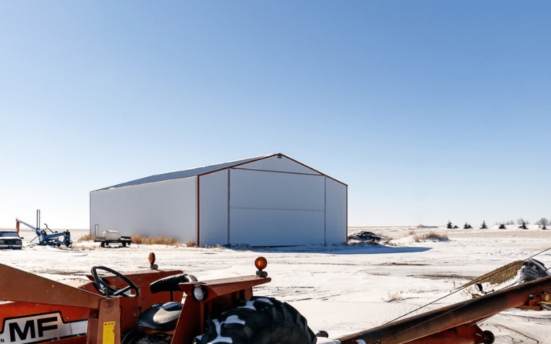 A bright white post-frame agricultural machine shed with a bifold door
