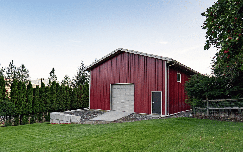 A dark red post-frame lifestyle & hobby shop with soffits and a overhead door