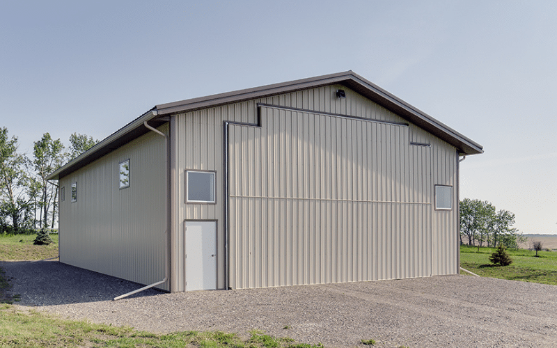 A light stone post-frame lifestyle & hobby shop with a bi-fold door and dark brown roof