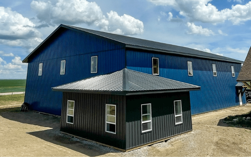 A heron blue post-frame lifestyle & hobby shop with timber accents, soffits, and overhead doors