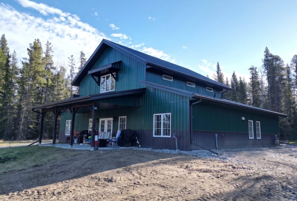 A post-frame melchers green residential barndominium with an attached garage