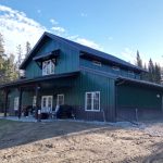 A post-frame melchers green residential barndominium with an attached garage