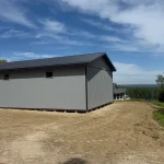 A regent grey post-frame lifestyle & hobby shop with soffits and a overhead door