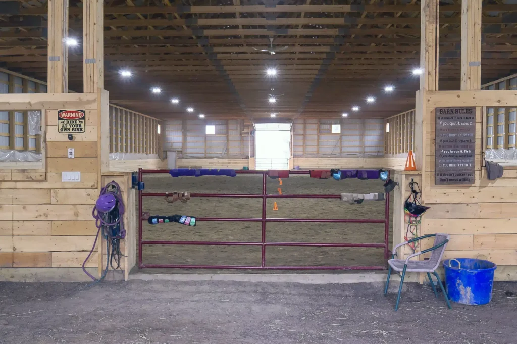 A bone white post-frame equestrian riding arena with sliding and overhead doors