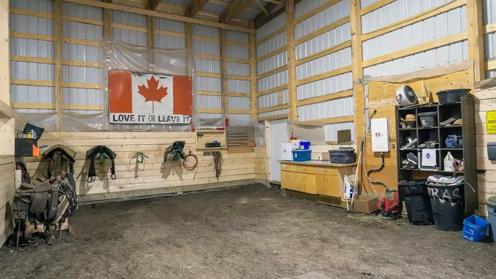 A bone white post-frame equestrian riding arena with sliding and overhead doors