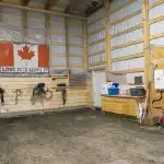 A bone white post-frame equestrian riding arena with sliding and overhead doors