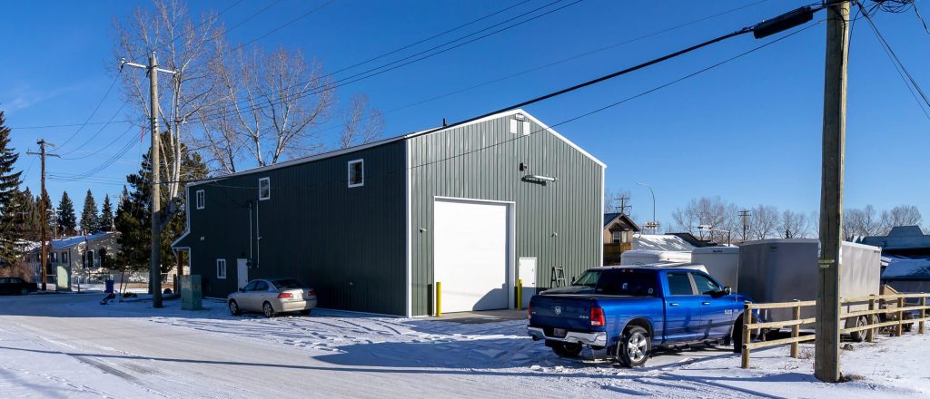 A dark sage commercial shop with a front porch and open lean-to