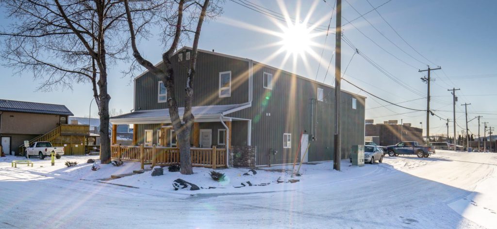 A dark sage commercial shop with a front porch and open lean-to