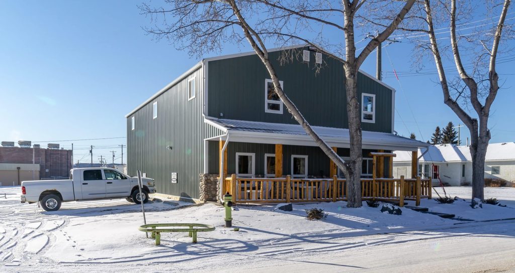 A dark sage commercial shop with a front porch and open lean-to