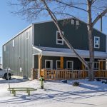 A dark sage commercial shop with a front porch and open lean-to