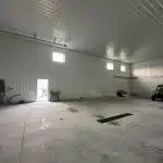 A regent grey post-frame lifestyle & hobby shop with soffits and a overhead door