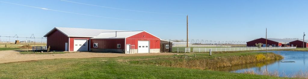 A dark red post-frame equestrian Shop with four overhead and four bi-fold doors
