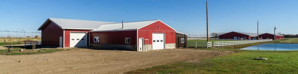 A dark red post-frame equestrian Shop with four overhead and four bi-fold doors